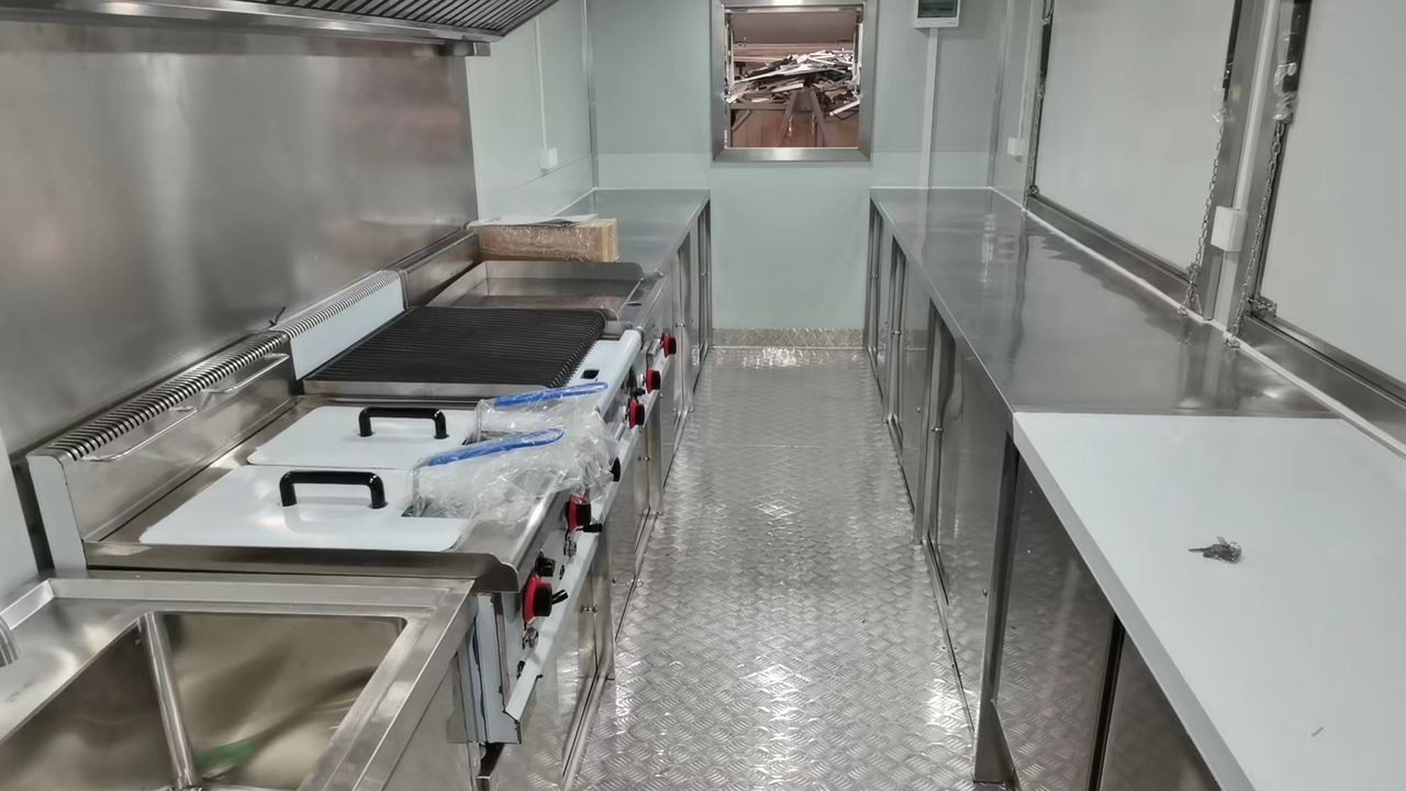 Interior view of a professional stainless steel kitchen with cooking equipment, sinks, and countertops.