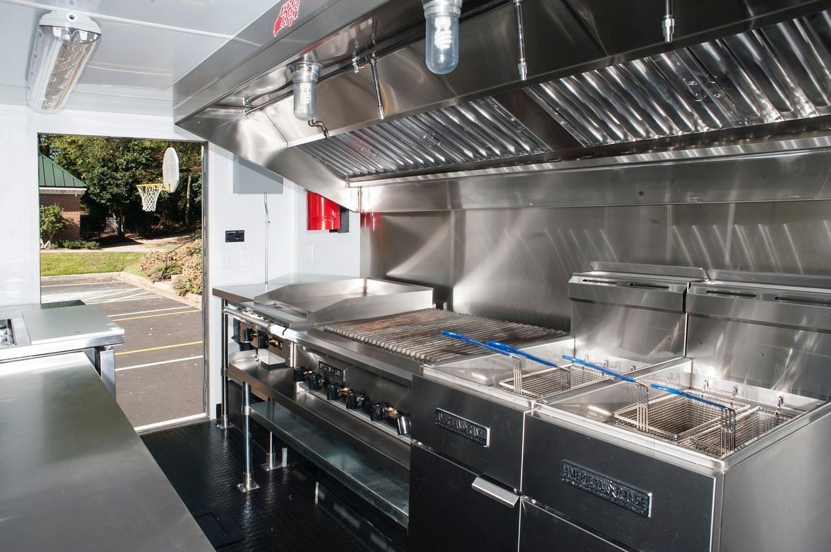 Interior of a modern food truck kitchen with stainless steel appliances and cooking equipment.